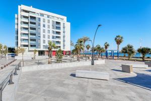 a large white building with palm trees and benches at Alma de Pacifico in Málaga