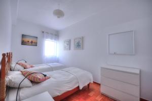 two beds in a bedroom with white walls at Margarida Seaview Terrace Apartment in Luz