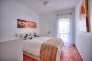a white bedroom with a bed and a window at Margarida Seaview Terrace Apartment in Luz