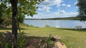 a bench sitting in the grass next to a lake at "Źródło zasilania" domki letniskowe nad Zalewem Chańcza in Raków +2 photos