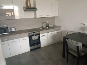 a kitchen with white cabinets and a sink and a stove at Mieszkanie do wynajęcia in Ostróda