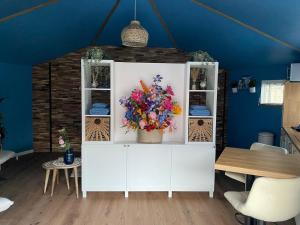a white cabinet with a bouquet of flowers on it at Van Egmond suites Mr Blue Sky in Anna Paulowna