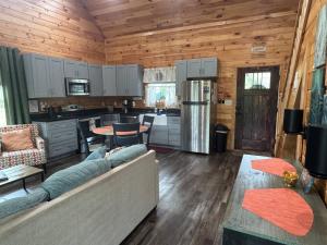 Hemlocks Over Muir in Rogers KY - Hot Tub & WiFi في Rogers: غرفة معيشة مع أريكة ومطبخ