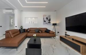 a living room with a brown couch and a flat screen tv at Villa Karla with pool&sea view by Villas Guide in Rab