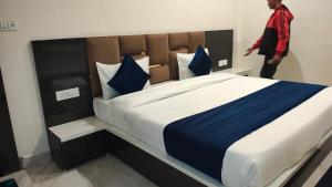 un hombre está de pie junto a una cama grande en Hotel basant, en Orchha