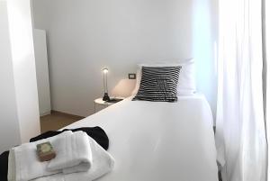 a white bed with a black and white pillow and a chair at MVM Apartment in Rome