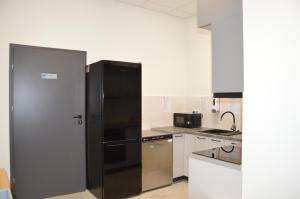a black refrigerator in a kitchen with white cabinets at Ośrodek Sportu i Rekreacji w Janowcu Wielkopolskim in Janowiec Wielkopolski