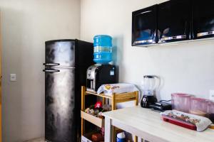 a kitchen with a refrigerator next to a table at Chalé 3 Reis Bg in Barra Grande
