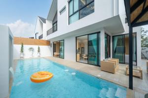 ein Schwimmbecken mit einem orangefarbenen Objekt in der Mitte eines Hauses in der Unterkunft Bangtao Brand New Luxury Modern Pool Villa Laguna Phuket in Thalang