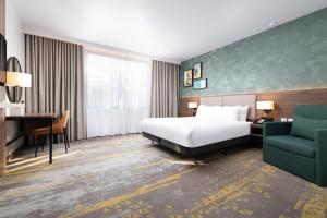 a hotel room with a bed and a desk and a chair at Holiday Inn London Gatwick - Worth by IHG in Crawley