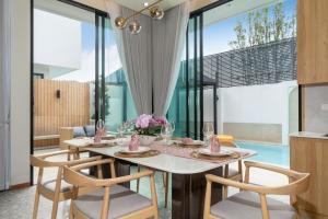 ein Esszimmer mit einem weißen Tisch und Stühlen in der Unterkunft Bangtao Brand New Luxury Modern Pool Villa Laguna Phuket in Thalang
