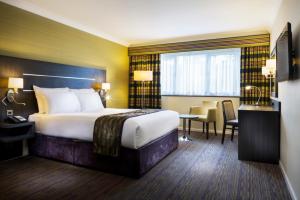 a hotel room with a large bed and a desk at Holiday Inn London Gatwick - Worth by IHG in Crawley +89 photos