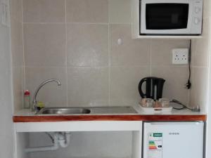 a small kitchen with a sink and a microwave at Stay @ Edison in Strand +25 photos