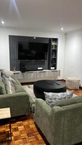 a living room with two couches and a tv at 8 on Lorenzo in Amanzimtoti