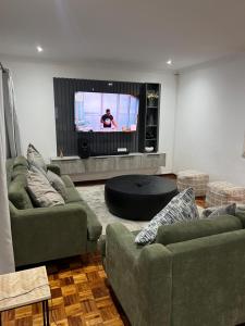 a living room with two green couches and a tv at 8 on Lorenzo in Amanzimtoti