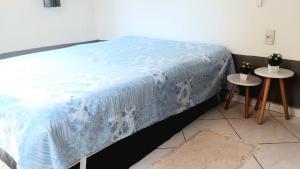 a bed with a blue blanket and two tables at BOIPEBA Cantinho do Mirko 1 in Cairu