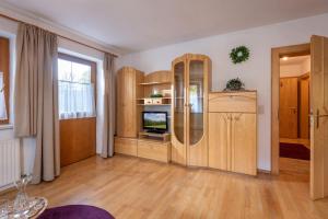 a living room with wooden cabinets and a television at Biobauernhof Enting Söll in Söll +3 photos