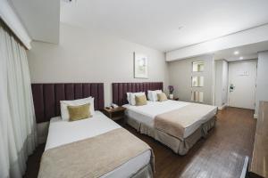 a hotel room with two beds and a window at Hotel Victoria Villa Curitiba by Nacional Inn in Curitiba