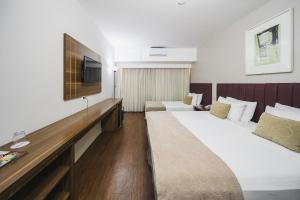 a hotel room with two beds and a flat screen tv at Hotel Victoria Villa Curitiba by Nacional Inn in Curitiba +76 photos
