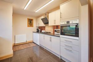a kitchen with white cabinets and white appliances at Host & Stay - Cherry Willows in Stainsacre