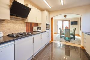 a kitchen with white cabinets and a dining room at Host & Stay - Cherry Willows in Stainsacre +18 photos