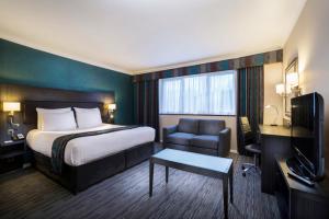 a hotel room with a bed and a chair at Holiday Inn London Gatwick - Worth by IHG in Crawley