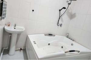 a white bathroom with a bath tub and a sink at 5 Bed Villa Sleeps 10 with Jacuzzi in Georgetown +18 photos