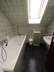 a bathroom with a tub and a sink and a window at Gästezimmer im Dachgeschoss in Rhede