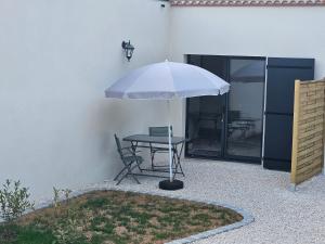 een tafel en een stoel onder een paraplu bij La Panurama in Prayssac