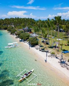 a boat in the water on a beach with palm trees at Hotel Bijoux in Plaridel