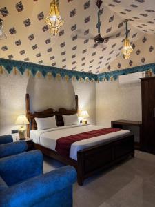 a bedroom with a bed and a blue chair at Estherea Bagh Ranthambhore Tiger Territory in Sawāi Mādhopur