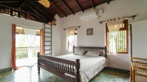una camera da letto con un letto in una stanza con finestre di Shaili - 3BHK Konkani Villa near Tamastirth beach, Dapoli a Dapoli