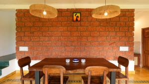 un tavolo da pranzo con sedie e un muro di mattoni di Shaili - 3BHK Konkani Villa near Tamastirth beach, Dapoli a Dapoli