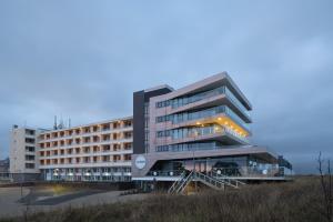 ein großes Gebäude mit einer Treppe davor in der Unterkunft Droomsuites Egmond aan Zee 8 personen by Droomvilla in Egmond aan Zee