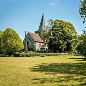 une vieille église avec un clocher sur un champ herbeux dans l'établissement White Cliff Rest, à Seaford