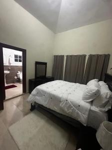 Puerto PlataにあるEspacioso Casa en Puerto Plata cerca de La Playa 4 camas 3 baños Agua caliente Aire condicionado Wi-Fiの白いベッドとバスルームのある寝室