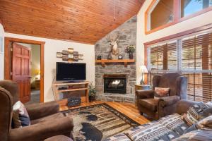 a living room with a stone fireplace and a television at Creekside - 2 BDR Resort Cabin in Epic Location in Branson West