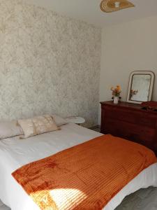 a bedroom with a bed with an orange blanket on it at Le Germini in Mirecourt
