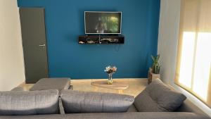 ein Wohnzimmer mit einem Sofa und einem Fernseher an einer blauen Wand in der Unterkunft Aranduroga in Corrientes