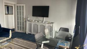 ein Wohnzimmer mit einem Glastisch und einem TV in der Unterkunft Seaside Escape in Thorpe Bay