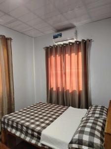 a bed in a room with a checkered curtain at PA L Residence in Euscara +5 photos