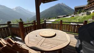 a wooden table on a deck with a view of mountains at Jean in Grimentz