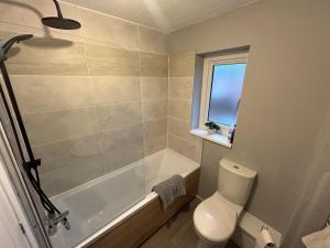a bathroom with a tub and a toilet and a window at 3 Bedroom, Parking, 2 Toilets, Wi-Fi, Modern in Crewe