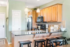 a kitchen with wooden cabinets and black counter tops at Sunset Daydream - Elegant Condo on Table Rock in Branson