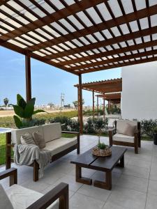 a patio with couches and a wooden pergola at Beach House - Private Dock and Pool in Cerro Azul