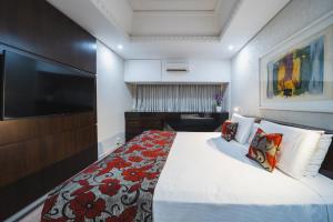 a bedroom with a large bed and a flat screen tv at Hotel Victoria Villa Curitiba by Nacional Inn in Curitiba