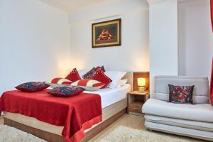 Un dormitorio con una cama con una manta roja y una silla. en Apartament B B Boutik C, en Eforie Sud 42 fotos más