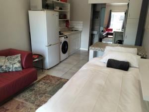 a living room with a white bed and a red couch at Feet Up Cottage in Somerset West +15 photos