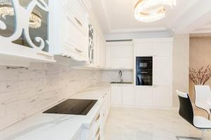 a white kitchen with white cabinets and white appliances at Central Elegant Apartment in Tbilisi City