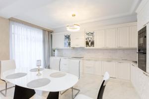 a white kitchen with a white table and chairs at Central Elegant Apartment in Tbilisi City